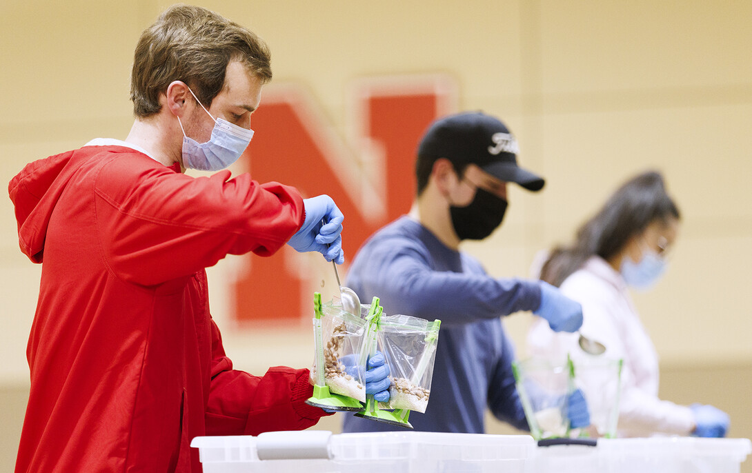 Caden Caverzagie adds a scoop of beans to a meal being packed in the Nebraska East Union on Jan. 20.