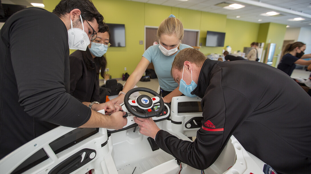 Huskers Ricardo Gato Gil (left) and Chandler Brock (right) work as a team with Yuqi Pu (second from left) and Caroline Sauer (both from UNMC) to prepare a car during the GoBabyGo! event.