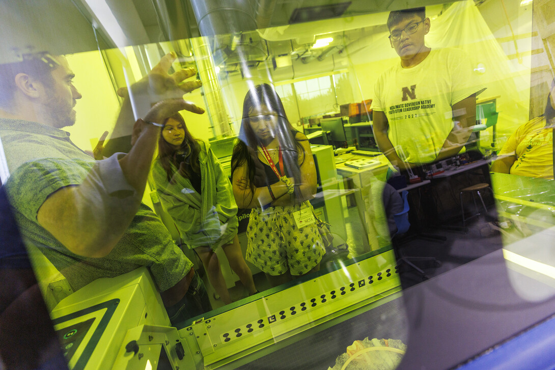 Max Wheeler (left), with Nebraska Innovation Studio, explains how the laser cutter works during the 2022 MATC/NCIA Sovereign Native Youth STEM Leadership Academy on June 30.