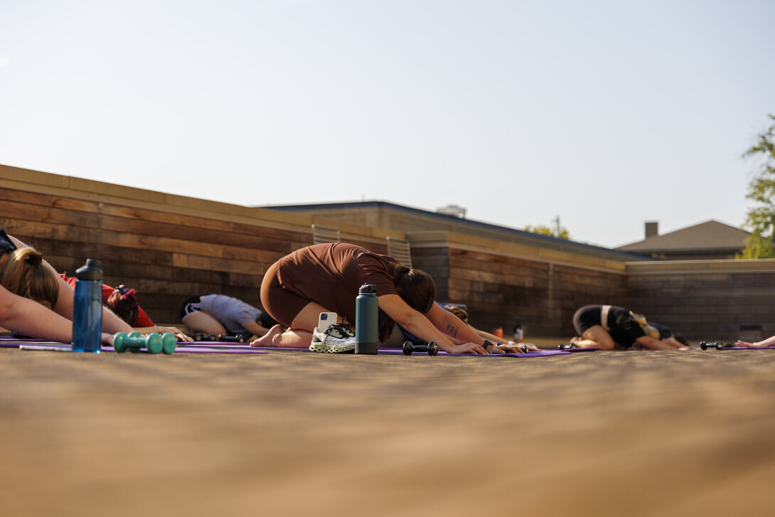 A participant finds child's pose in an outdoor group fitness class.