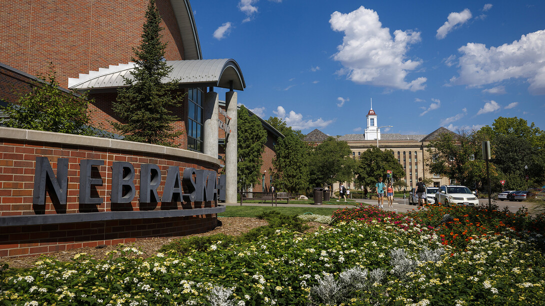 Photo of flowers blooming in front of the Van Brunt Visitors Center with Love Library in the distant background.