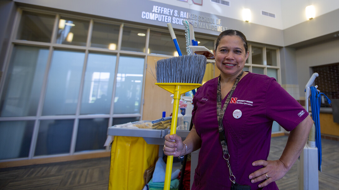 University Housing's Saira Bautista de Preciado stands proudly, holding a broom, in Kauffman Hall. Bautista de Preciado has worked as a custodian in the Raikes School for 10 years. She recently was awarded an Employee Service Award for her dedication to the university.