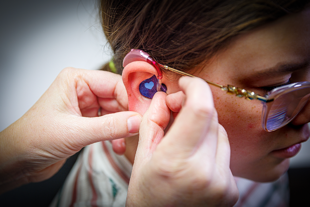 Ear with hearing aid being checked by audiologist