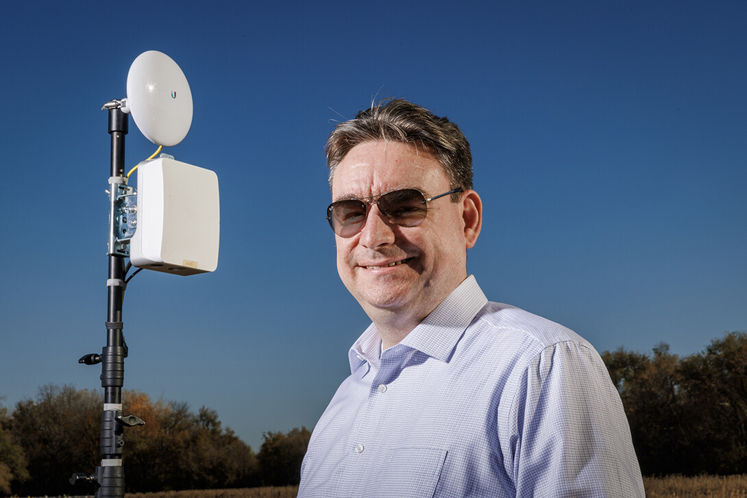 Mehmet Can Vuran lead member of the Field-Nets research team poses in a soybean field on east campus field with a Millimeter-wave (mmWave) radio with phased-array antennas.