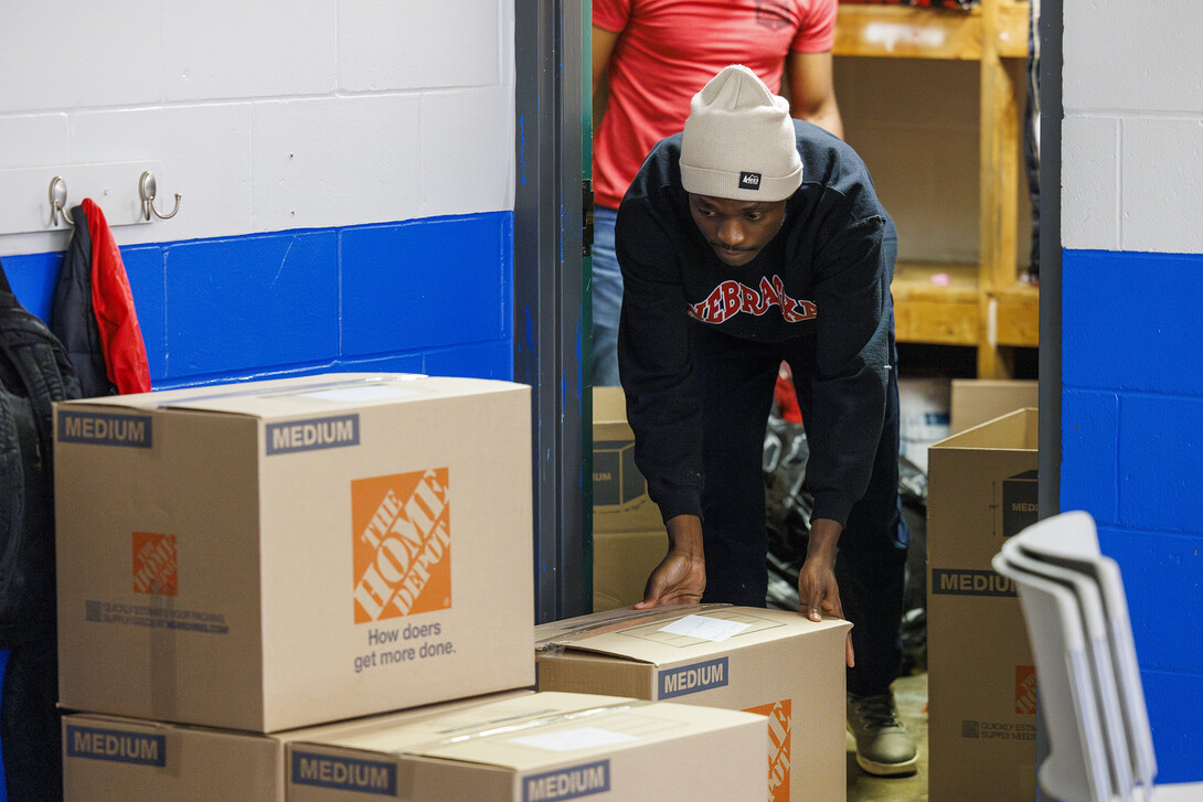 Emmanual Audu, a masters student, slides out a filled box from a Malone Center storage closet.  The center is moving out in the next few weeks to temporary locations while a new center is built on the site.