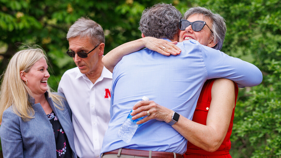 College of Law Dean Richard Moberly, dean of law, hugs Jane Green (right) as Ronnie Green talks with Christine Truhe, senior director of development for the College of Law.