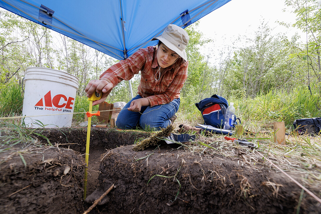Madeira Henclewood, a senior in anthropology uses a bubble level on the string to check that the square she is excevating is dug down properly.