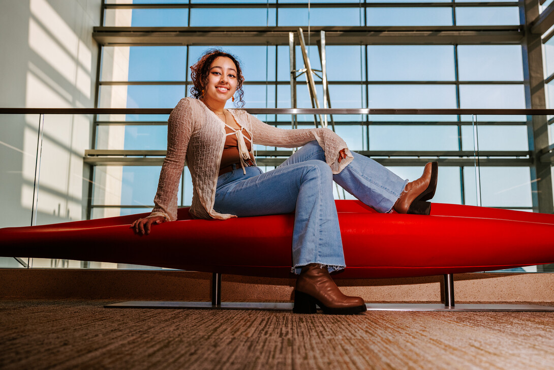 Ale poses for a photo on a bench in Hawks Hall