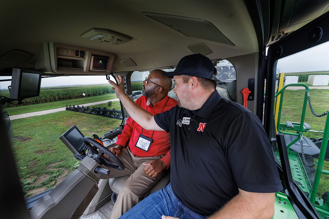 Chancellor Rodney Bennett rides in the cab of a John Deere sprayer.