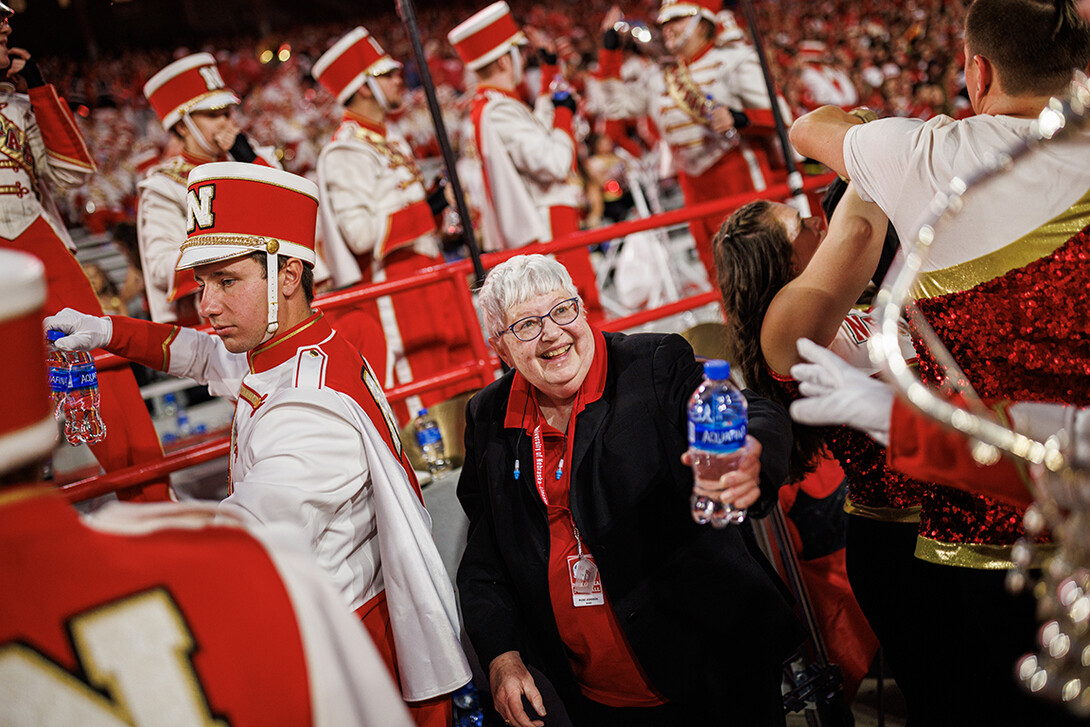 Rose Johnson with the Cornhusker Marching Band hands out water to the band members as they return to the stands following the half time show during the NU v. Northern Illinois game.