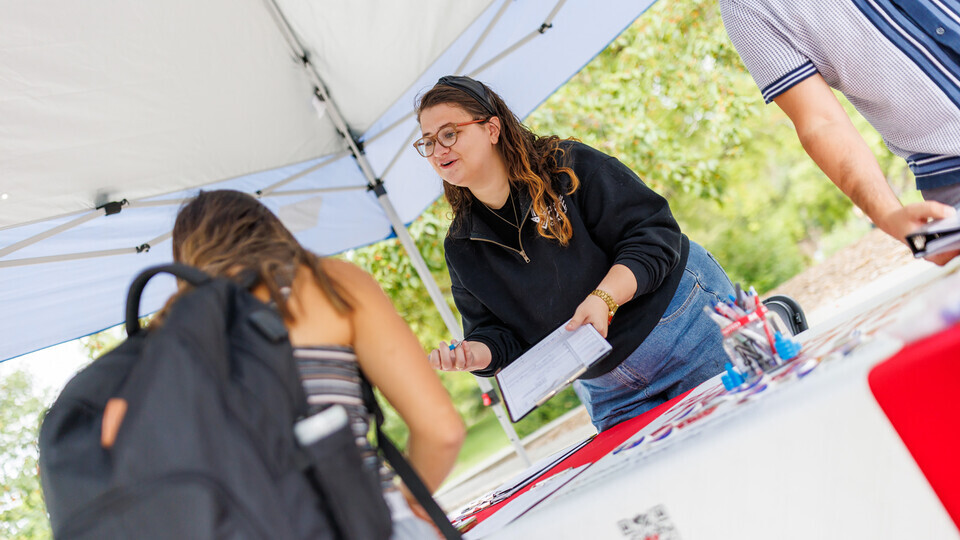 Maggie Nielsen with the Husker Vote Coalition provides voter registration information to a student. [Craig Chandler | University Communication and Marketing]