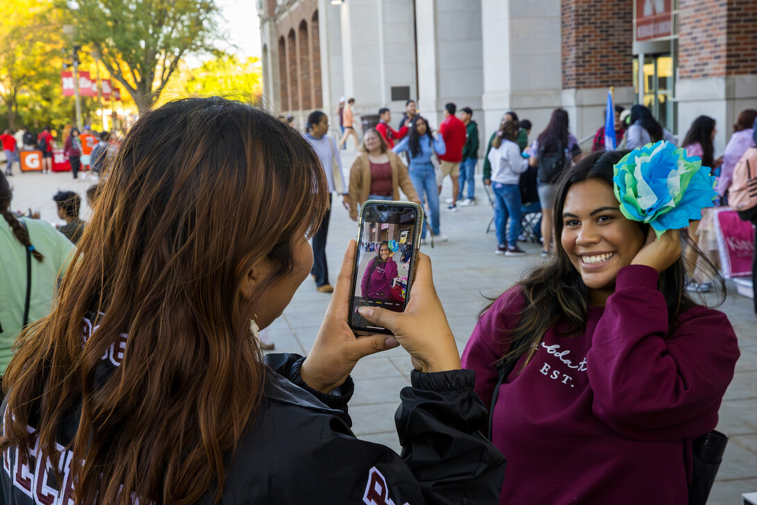 Lambda Theta Nu Sorority helped visitors make tissue paper flowers. A student models her creation.