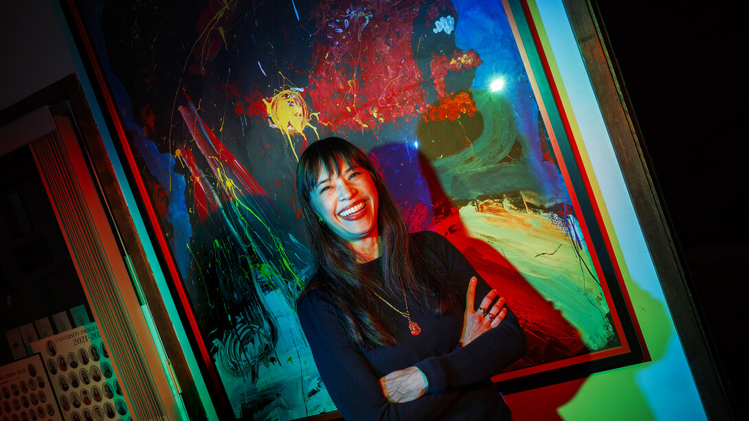 Nebraska's Karen Wills smiling while standing in front of an abstract, multi-colored painting.