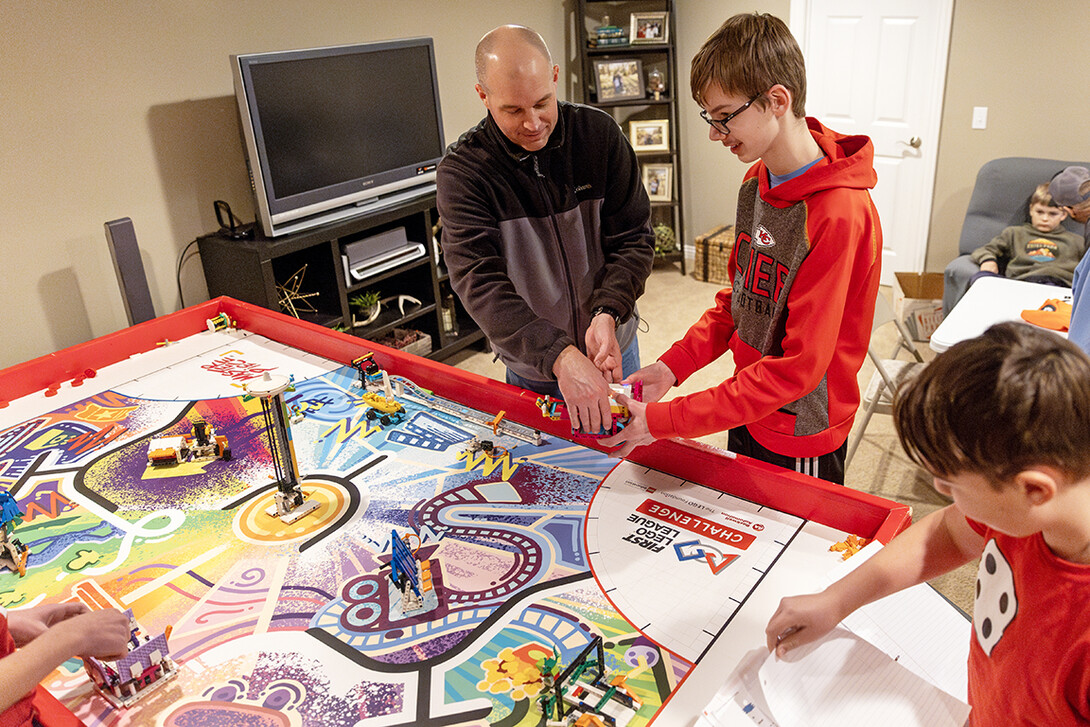 Coach Jordan Dowdy works with members of the team on their robot.