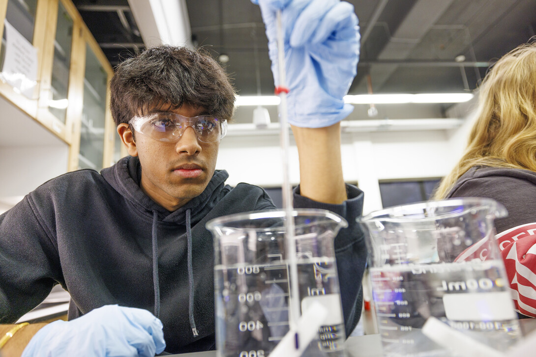 Abhi Karri checks the temperature of liquid in a beaker in a laboratory exercise.