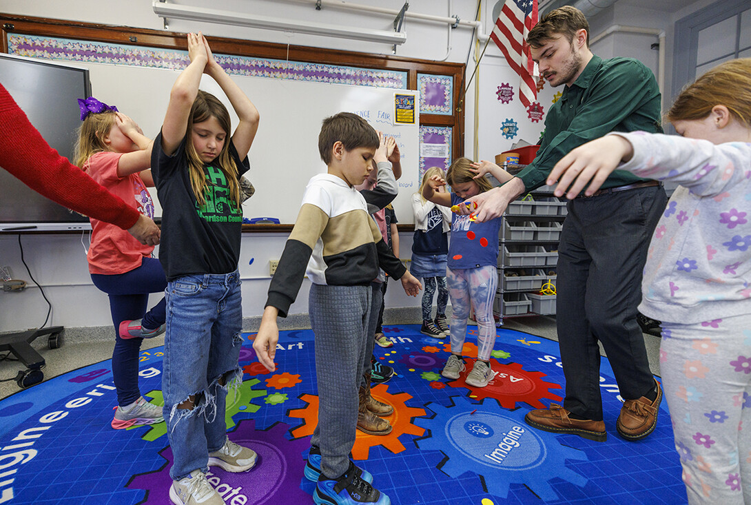 While students close their eyes and pretend they are trees, Jack Hilgert, drops red, yellow and blue chips on the floor.  The chips represent nutrients, sunshine and water. The students then open their eyes and scramble to pick up a balance of chips to help their “trees” grow.