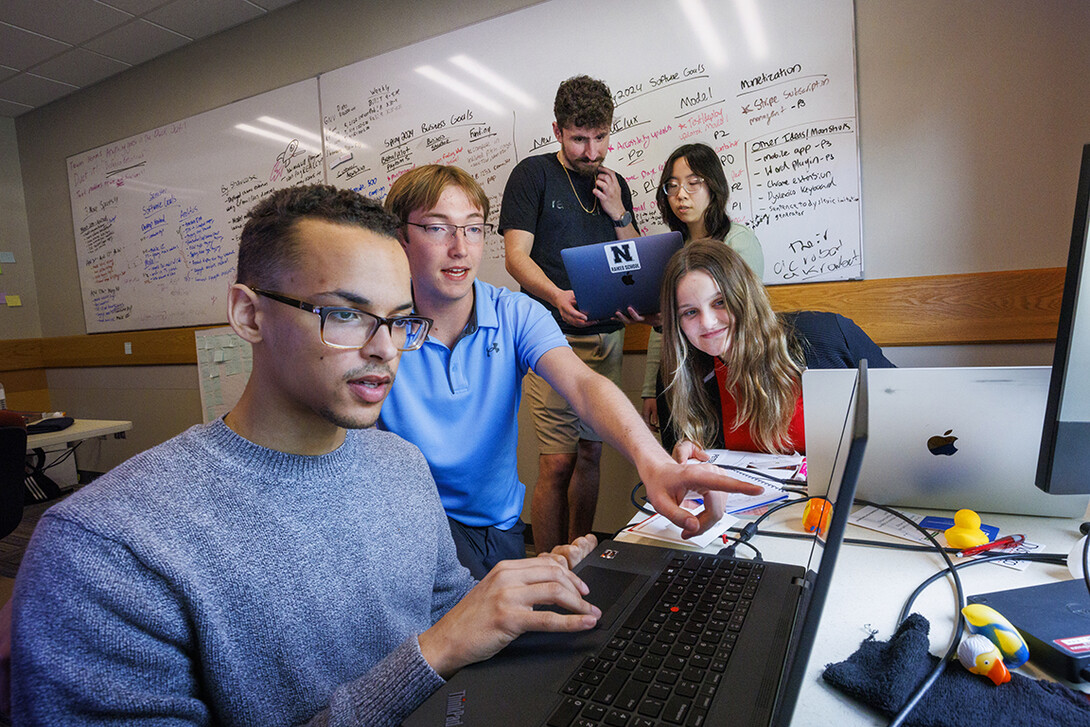 Dyslexico team members Tristan Curd, Nick Lauver and Bridget Peterkin look over data while, in back, Santiago Giraldo and Victoria Chin compare notes.