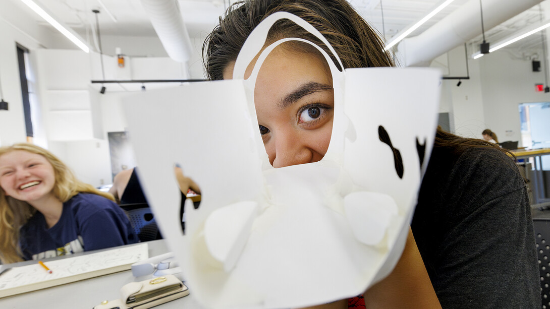 A student's eye is framed by a doorway on a paper model of a Sheldon Museum of Art plaza design. The work was part of a College of Architecture workshop for high school students.