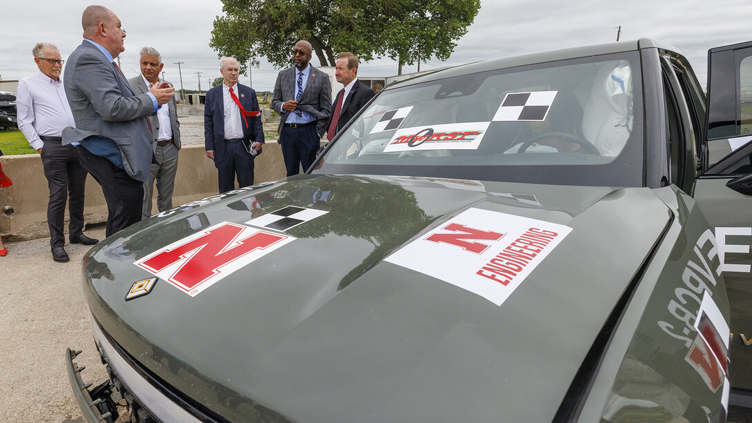 Researchers and campus leaders stand next to an EV that was used as part of a crash test on July 1.