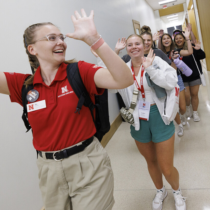 An NSE orientation leader and students celebrate while touring a campus building.