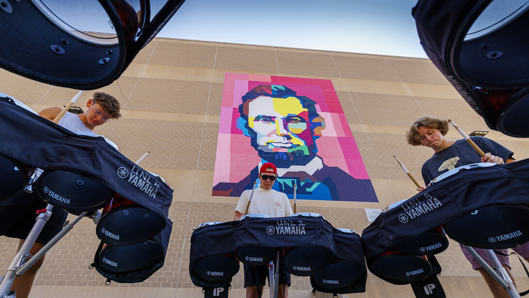 Members of the Cornhusker Marching Band’s quad line practice under the watchful gaze of a quilt-inspired mural of Abraham Lincoln. The mural, located on the west side of the Lied Center for Performing Arts, is based on an award-winning quilt made by New York-based artist Kim Soper. The quilt has been part of the collection of UNL’s International Quilt Museum since 2019.