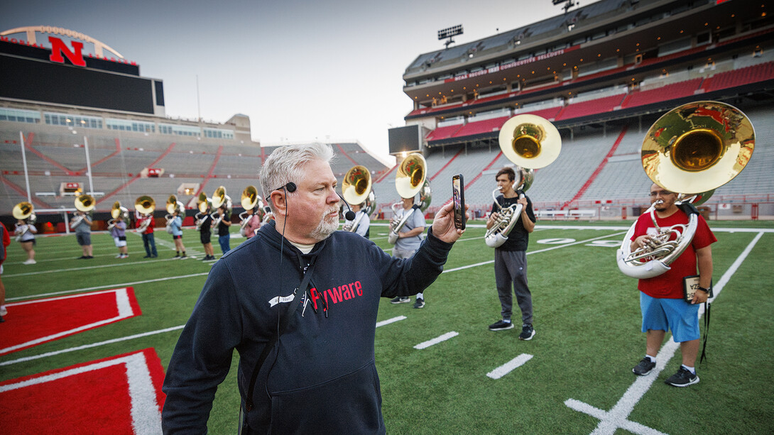 Doug Bush, assistant director of bands, walks through the band as it rehearses while doing a Facebook Live broadcast. Bush said he does the broadcasts on Friday practices and the game-day practice for all the parents and alumni who can’t come to the game. 