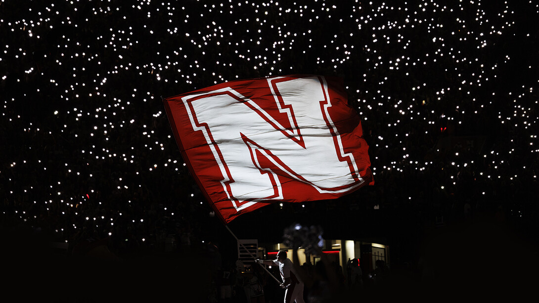 Jake Seip, a senior biological systems engineering major and member of the Husker Cheer Squad, waves the Nebraska flag on the turf in Memorial Stadium on Sept. 20. 