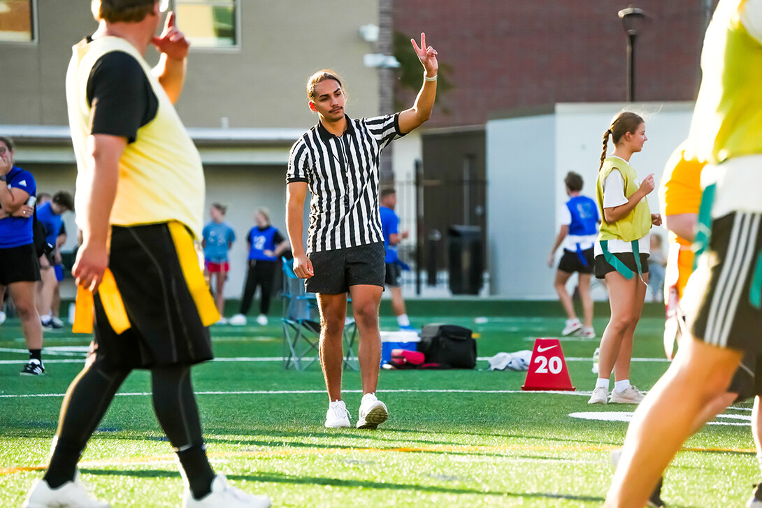 A referee holds up his hand to signal to players during an intramural flag football game.