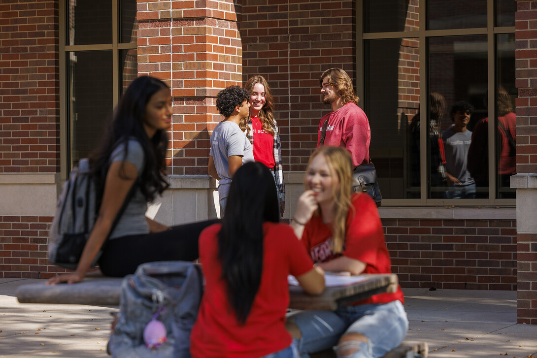 Viraj Karthik, Nick Coldiron, and Kate McKinzie talk outside the Raikes school as they enjoy the fall sunshine. 