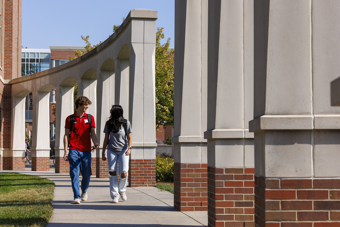 Raikes School students Gannett Bishop and Nina Glick walk along the columns outside of the Kauffman Academic Residential Center.