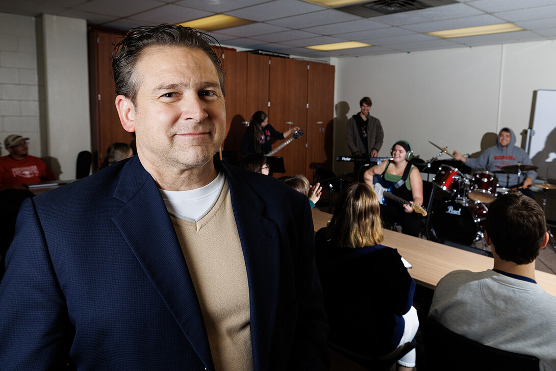 A man stands in front of a group of students playing musical instruments.