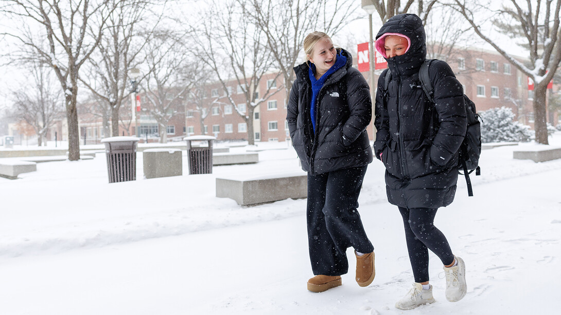 Students talk as they across a snow-covered Nebraska Union Plaza.