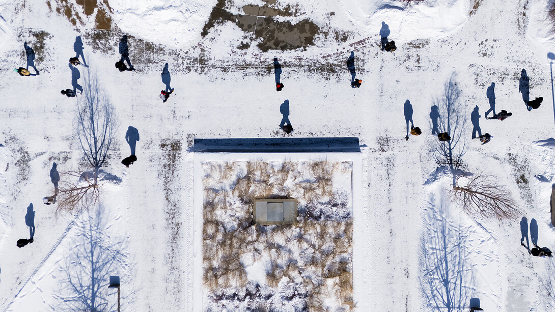 Aerial view of students crossing campus in the snow. 
