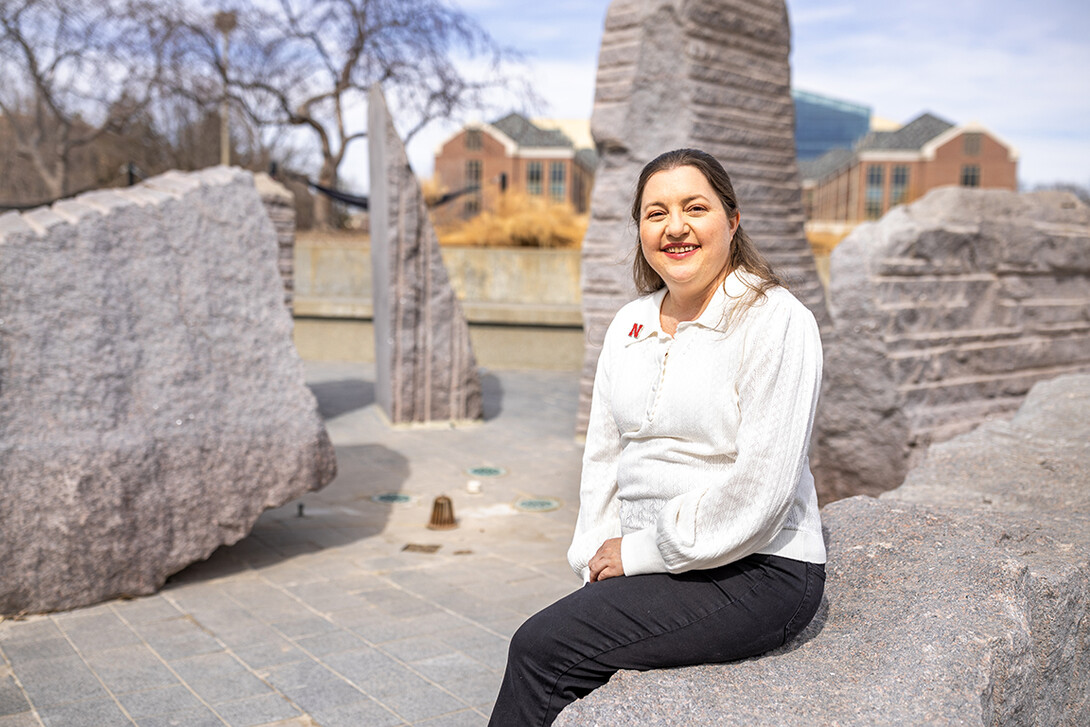 Courtney Santos, the director of Undergrad Research and Fellowships and an educational psychology graduate student, sits by Broyhill Fountain outside the Nebraska Union.