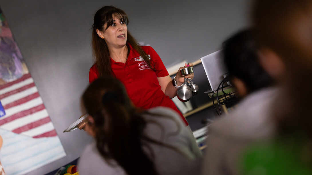 Zahraa Rida holds up cup measurements, which she used to demonstrate the amount of fruits, vegetables, grains and proteins are healthy to eat in a balanced diet.