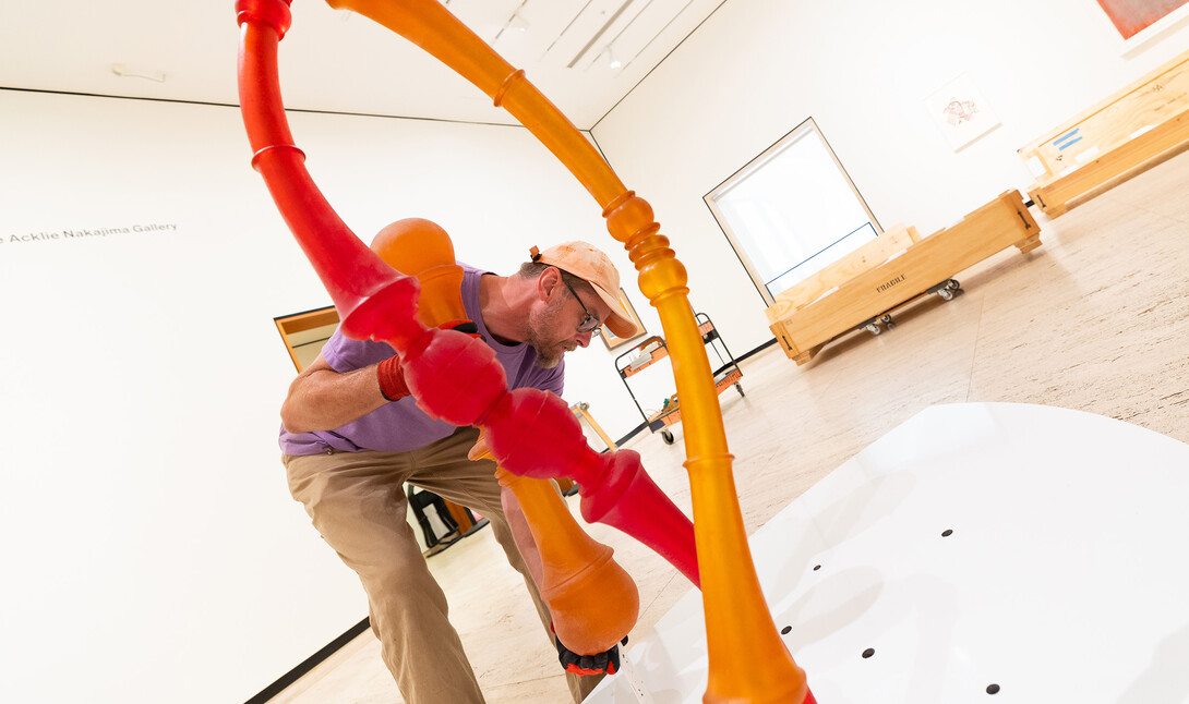 Delan Lonowski, on-call exhibition technician for the Sheldon Museum of Art, fits one of the smaller pieces of Niho Kozuru's sculpture, "Transplanted," into a stand