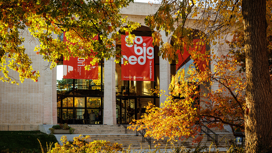 Yellow leaves shine in the sunlight and across the "Go Big Red" banner at Sheldon Museum of Art.