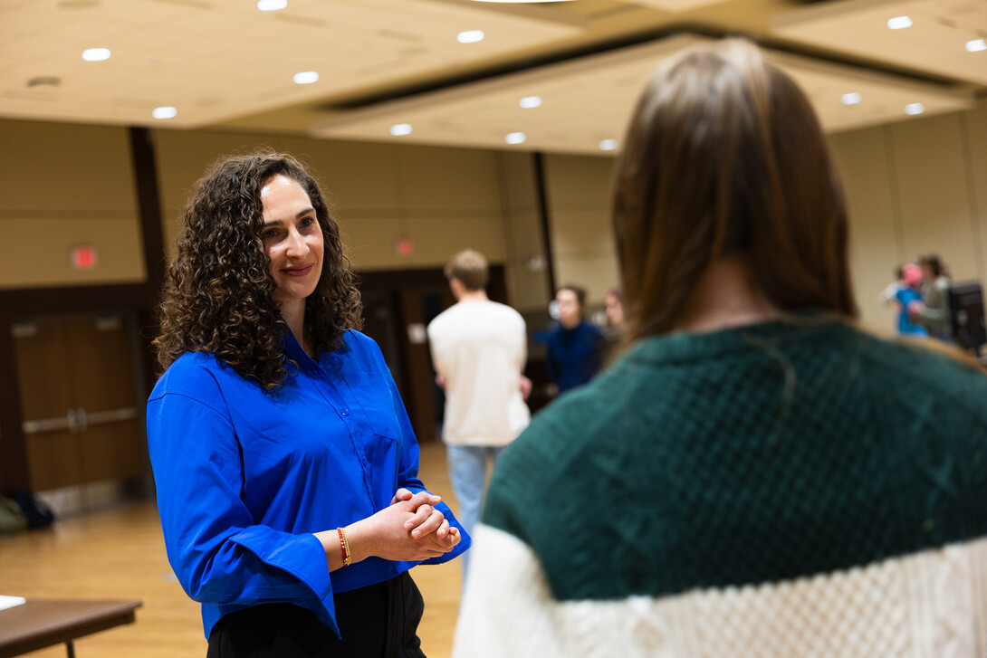 Two people talk, one facing the camera.