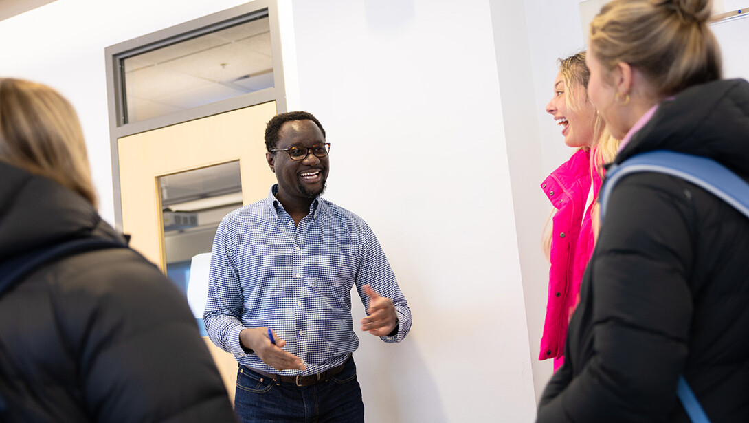 Dane Kiambi, associate professor of advertising and public relations, chats with students after a morning class in Andersen Hall.