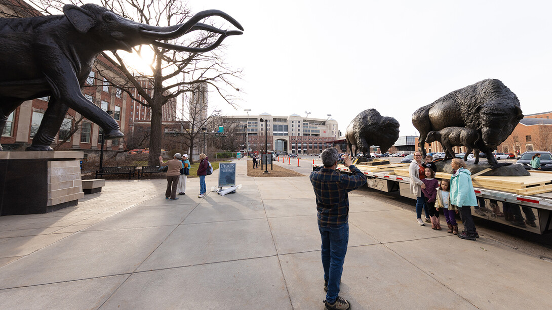 A family takes a photo in front of bronze bison sculptures created by Nebraska artist Gary Staab.