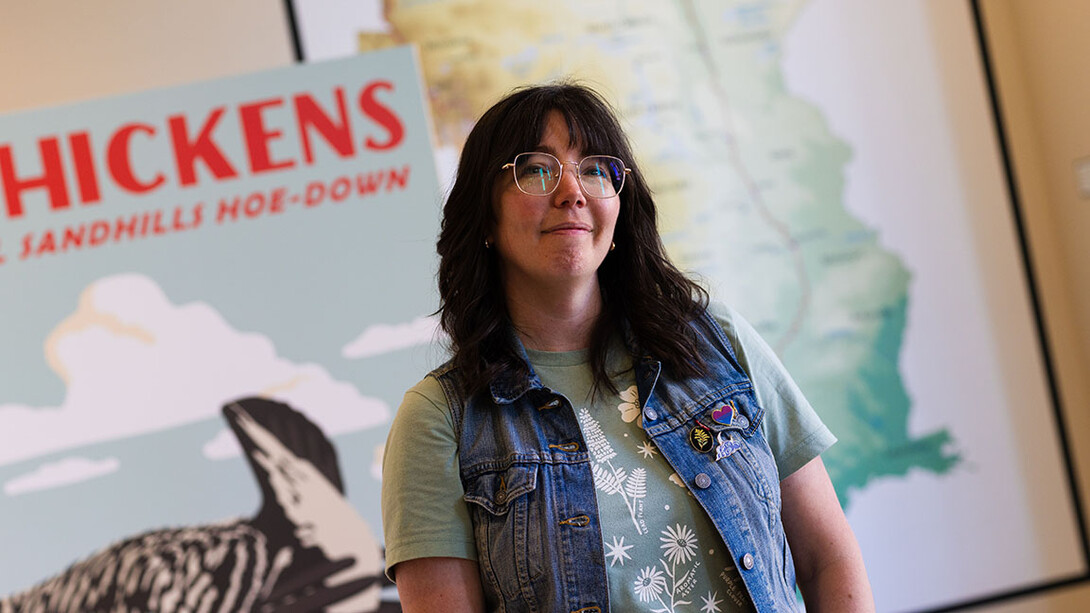 A woman stands in front of two wall hangings
