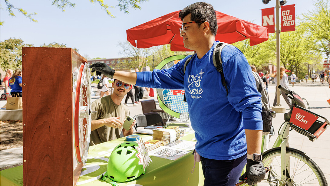 Rashed Hasan spins a wheel at the Bike LNK booth to learn more about sustainability at Earthstock at the Nebraska Union Plaza.