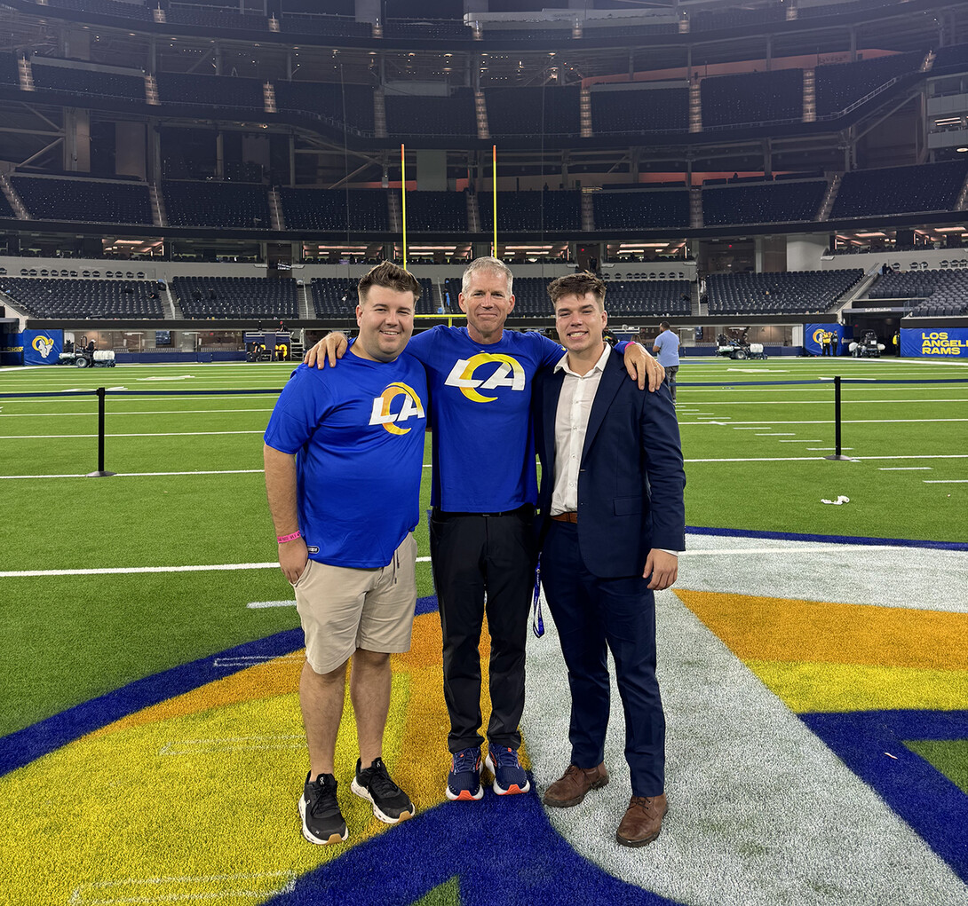 Three guys standing on the turf in SoFi Stadium.