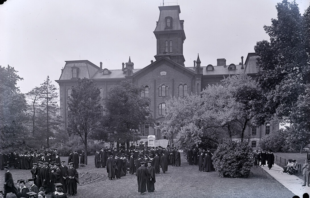 Graduates gather in front of University Hall, the first building on campus.
