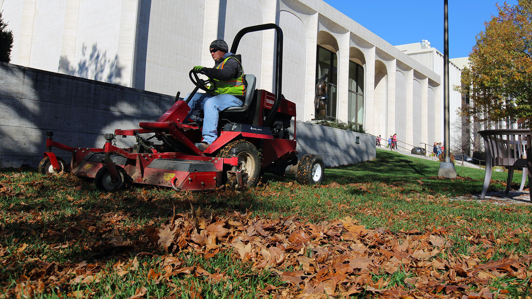 Tim Herron, a landscape assistant with landscape services, mulches leaves into the grass on the east side of Sheldon Museum of Art on Nov. 8. The university recently expanded it's sustainability practices by partnering with Big Red Worms on leaf recycling.