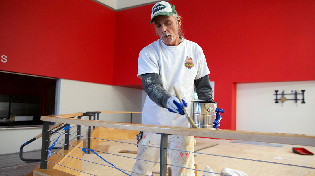 Mike Shore applies stain to wood on the warm viewing stand inside the John Breslow Ice Hockey Center.