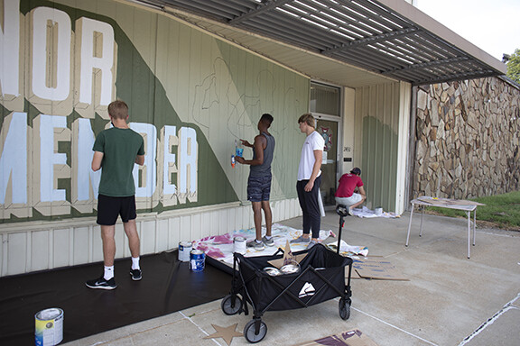 Students from Associate Professor of Art Sandra Williams’ University Honors seminar Graffiti Revolution help Shawn Dunwoody (second from left) paint his mural at the Veterans of Foreign Wars at 2431 N. 48th St. Photo by Eddy Aldana.