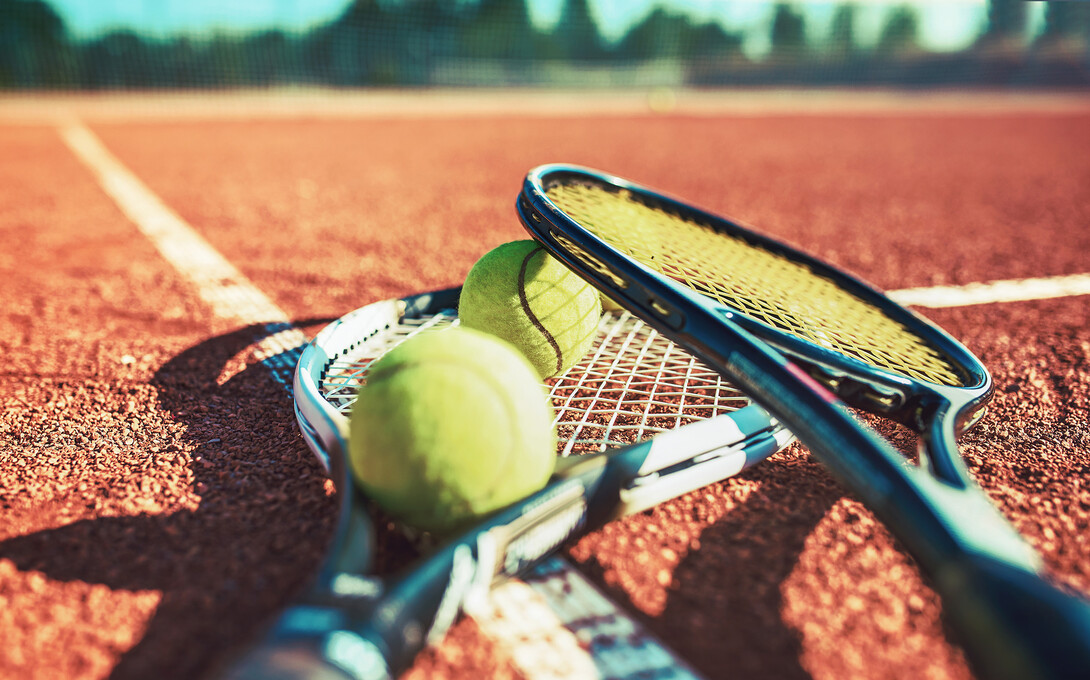 tennis rackets and two yellow tennis balls lay on a tennis court