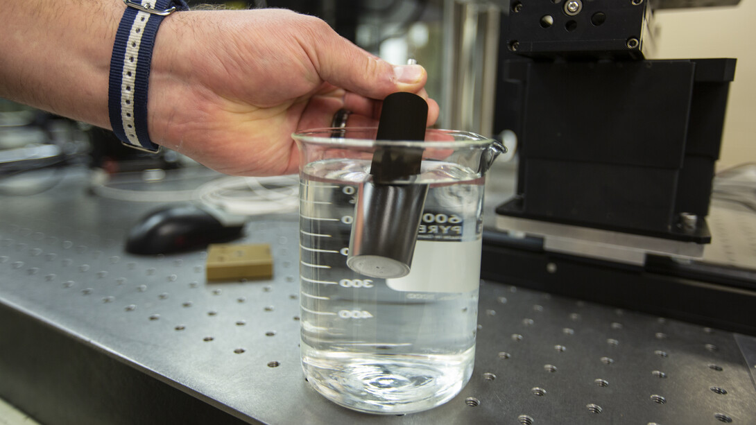 A metal sample modified to mimic shark skin repels water as it is placed in a beaker. The modified metal may some day be used to create submersibles that can travel more efficiently through water.