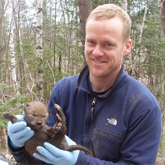 John Benson holding a wolf cub.